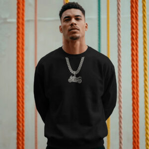 Person wearing a black sweatshirt with a silver motorcycle chain graphic, standing in front of colorful hanging ropes in an indoor setting.