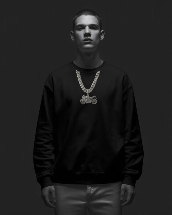 Person wearing a black sweatshirt with a gold motorcycle chain graphic, standing against a dark background with dramatic lighting