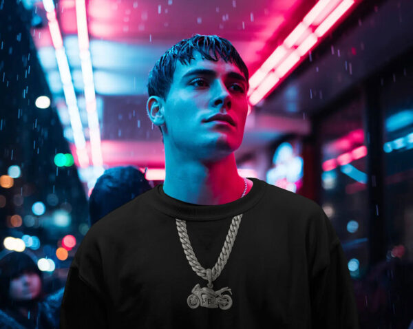 Person wearing a black sweatshirt and motorcycle chain pendant standing under neon lights in a rainy night time city scene