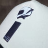 close up of an embossed black MIB logo print on the front of a cream cap