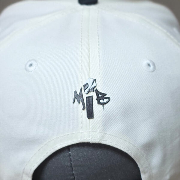 small embossed MIB drip print logo on the back of a cream cap